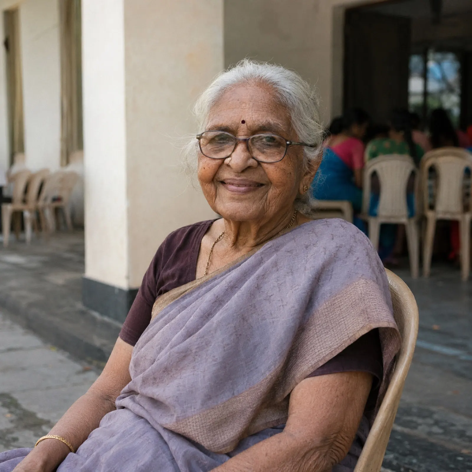 An elderly woman in a sari smiling at a senior citizens gathering